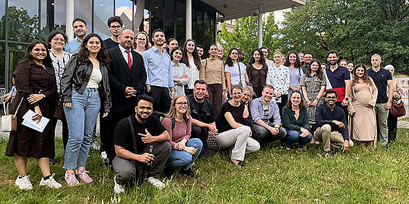 Treffen junger Ärztinnen und Ärzte in Bochum: Gruppenfoto mit mehreren jungen Erwachsenen auf einer Wiese vor einem Gebäude.